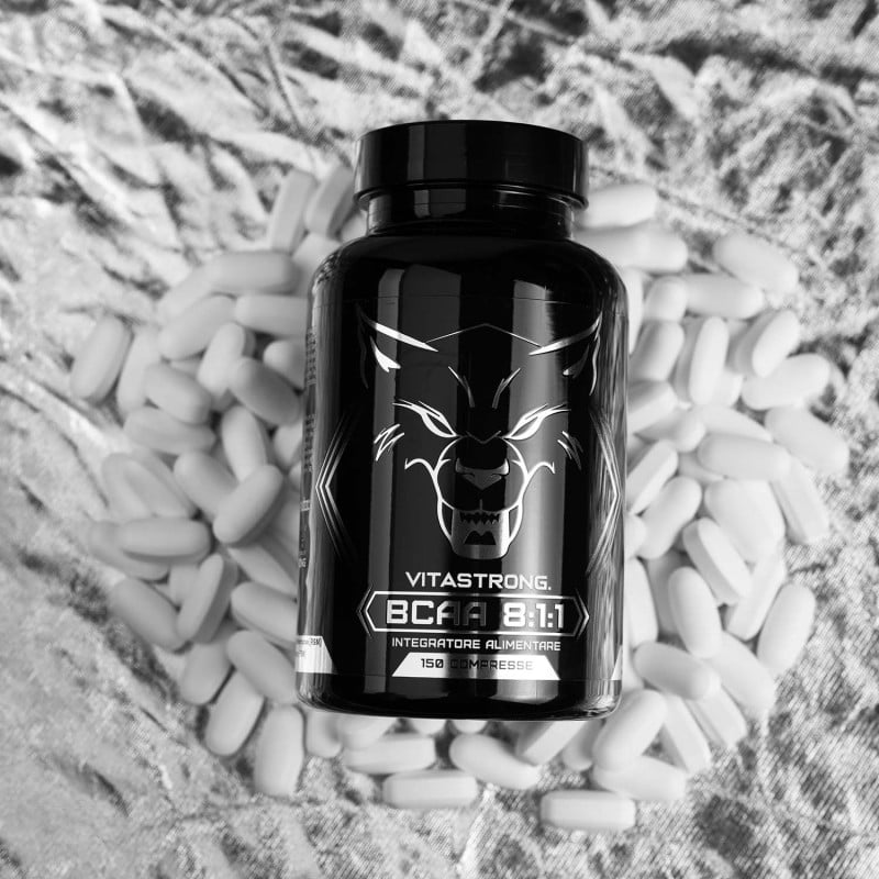 Black supplement bottle labeled 'Vitastrong' on a bed of white capsules.
